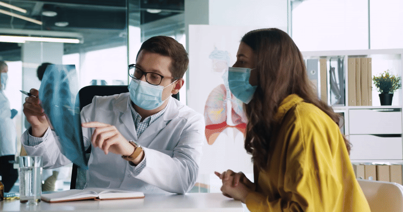 a man and a woman wearing face masks reviewing medical images together